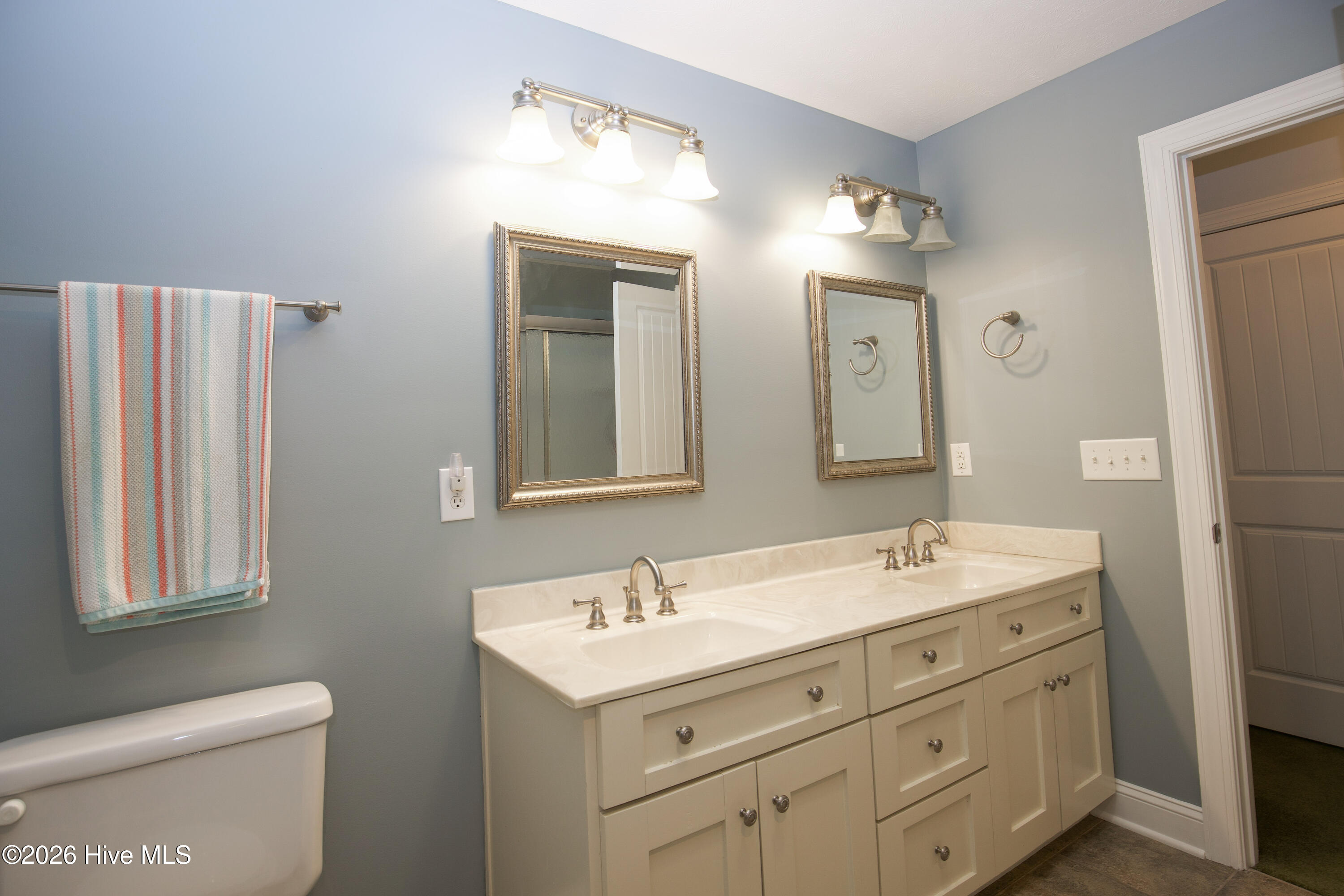45 Richmond Road Jackson Springs, NC 27281 - Photo 66 of 93 This well-appointed upstairs bathroom combines style and convenience, featuring a spacious double vanity with elegant marble-look countertops and ample drawer storage. Two framed mirrors and updated light fixtures add a touch of sophistication, while the soft wall color creates a calming atmosphere. Conveniently located between the upstairs bedrooms, it’s ideal for shared use without compromising on comfort or privacy. A perfect blend of form and function for guests or additional household members.