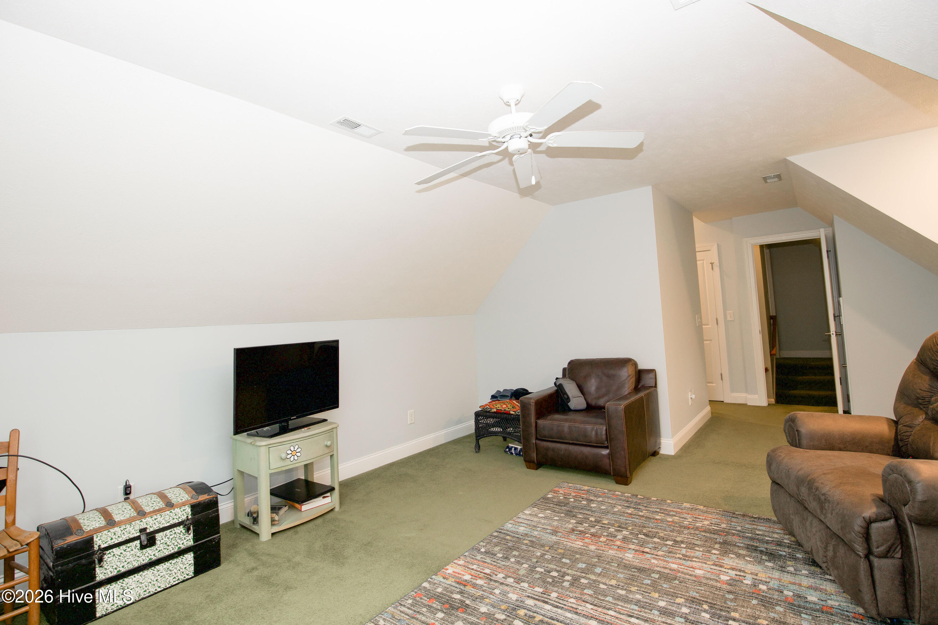 45 Richmond Road Jackson Springs, NC 27281 - Photo 70 of 93 This spacious upstairs bedroom offers exceptional flexibility to meet a variety of needs. Currently styled as a comfortable sitting room, this large, light-filled space features charming dormered ceilings, soft wall tones, and a ceiling fan for added comfort. The thoughtful layout allows this room to function beautifully as a private bedroom, home office, media lounge, or hobby space. With a dedicated entrance and convenient access to a full bath, it’s ideal for guests or anyone seeking a quiet retreat. Whether you envision a cozy reading nook, creative studio, or additional living area, this room adapts effortlessly to your lifestyle.
