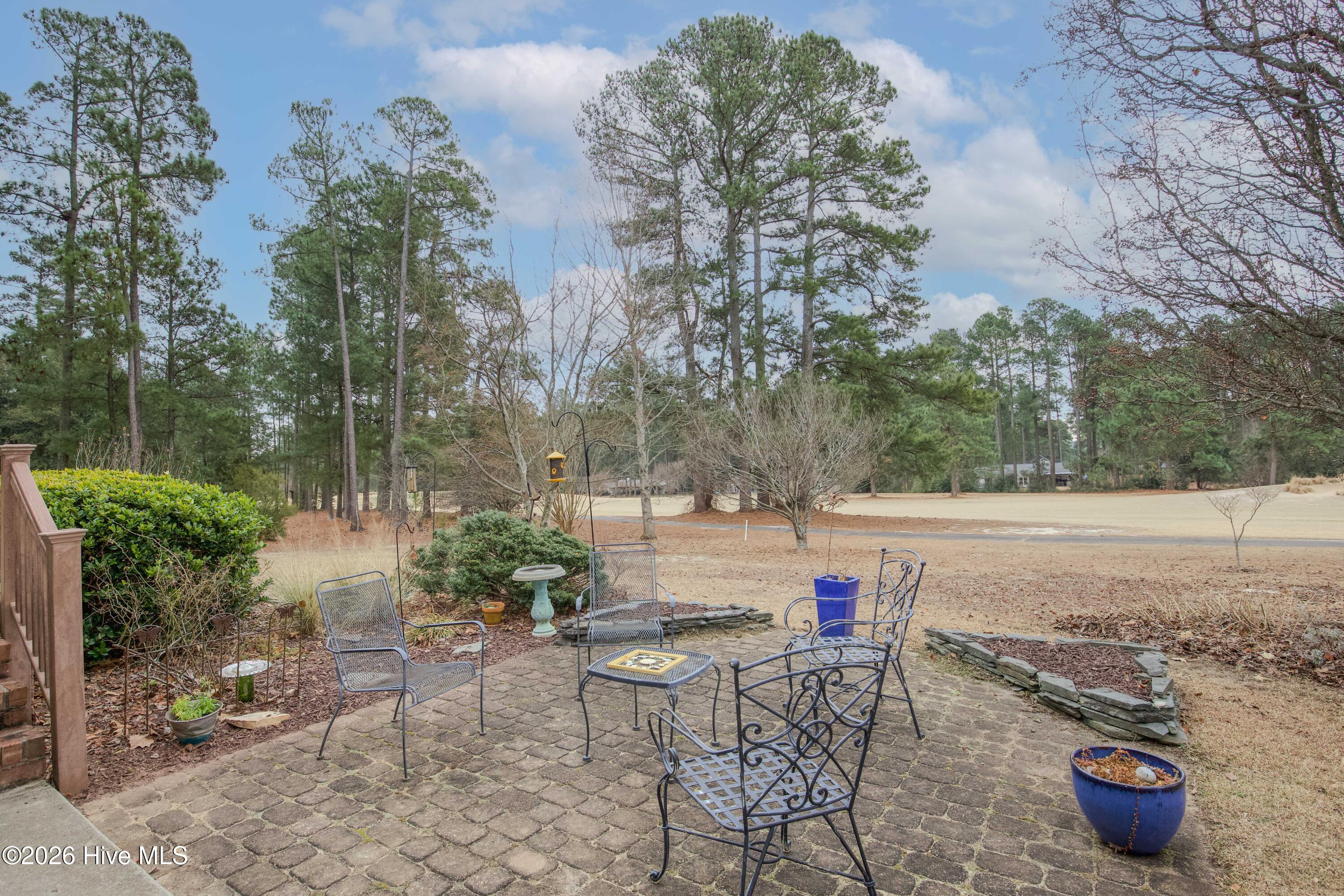 45 Richmond Road Jackson Springs, NC 27281 - Photo 77 of 93 Step outside to this inviting patio that opens directly to golf course views. With mature trees and cozy seating, it's the perfect space to enjoy morning coffee or unwind at sunset, surrounded by nature and serenity.