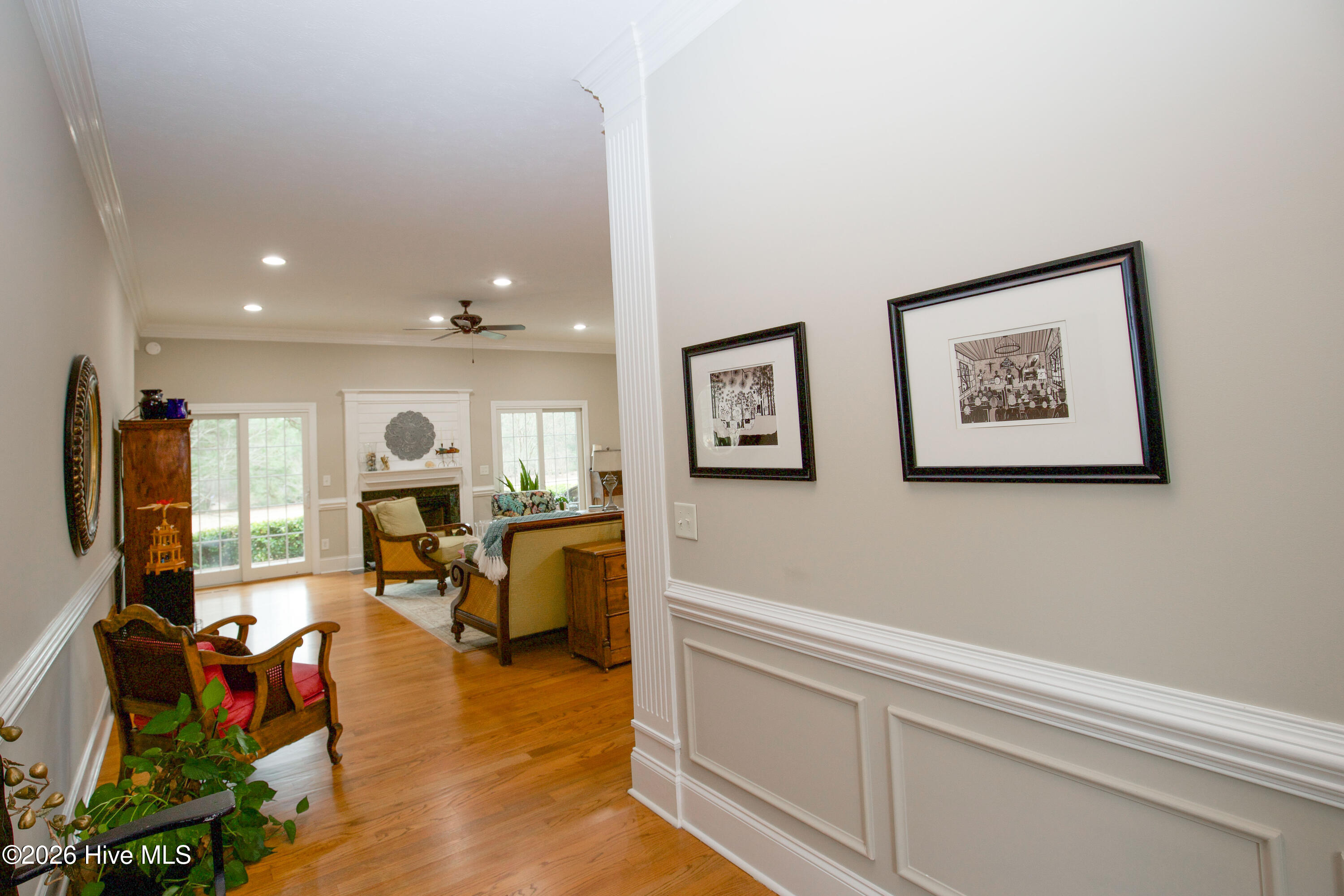 45 Richmond Road Jackson Springs, NC 27281 - Photo 8 of 93 Step into elegance from the moment you enter the home, where the foyer greets you with rich hardwood floors, refined wainscoting, and crown molding details. The open sightline draws your attention to the inviting living room beyond, featuring a cozy fireplace and abundant natural light pouring in through double glass doors. This seamless flow creates a warm, welcoming atmosphere perfect for everyday living or entertaining.