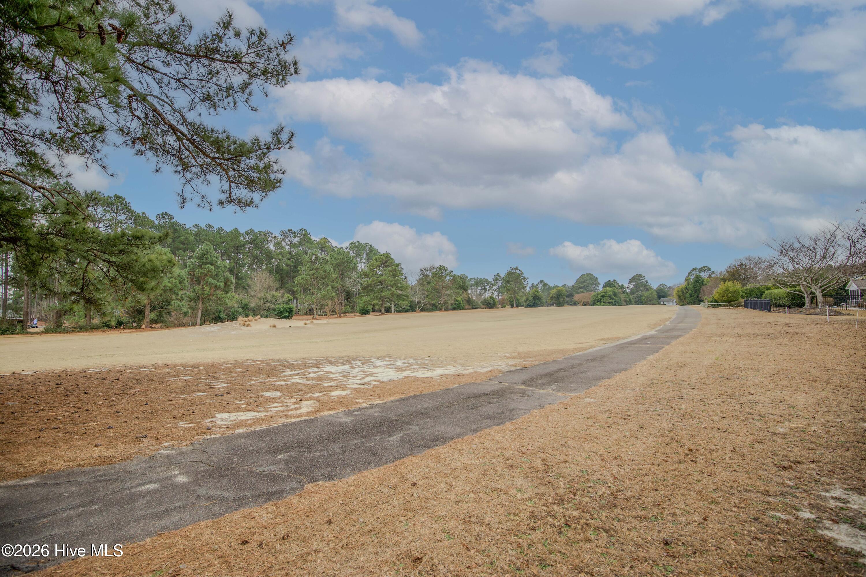 45 Richmond Road Jackson Springs, NC 27281 - Photo 83 of 93 Enjoy sweeping views of the Red Fox Course at Foxfire from your backyard at 45 Richmond Rd in Jackson Springs, NC. This scenic vista showcases the expansive fairway and golf cart path, framed by mature pines and open sky. The tranquil setting is perfect for golf enthusiasts and those who appreciate peaceful, picturesque surroundings , an ideal backdrop for outdoor living, relaxation, and entertaining.