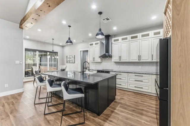 a kitchen with stainless steel appliances granite countertop a stove top oven a sink dishwasher and a refrigerator with wooden floor