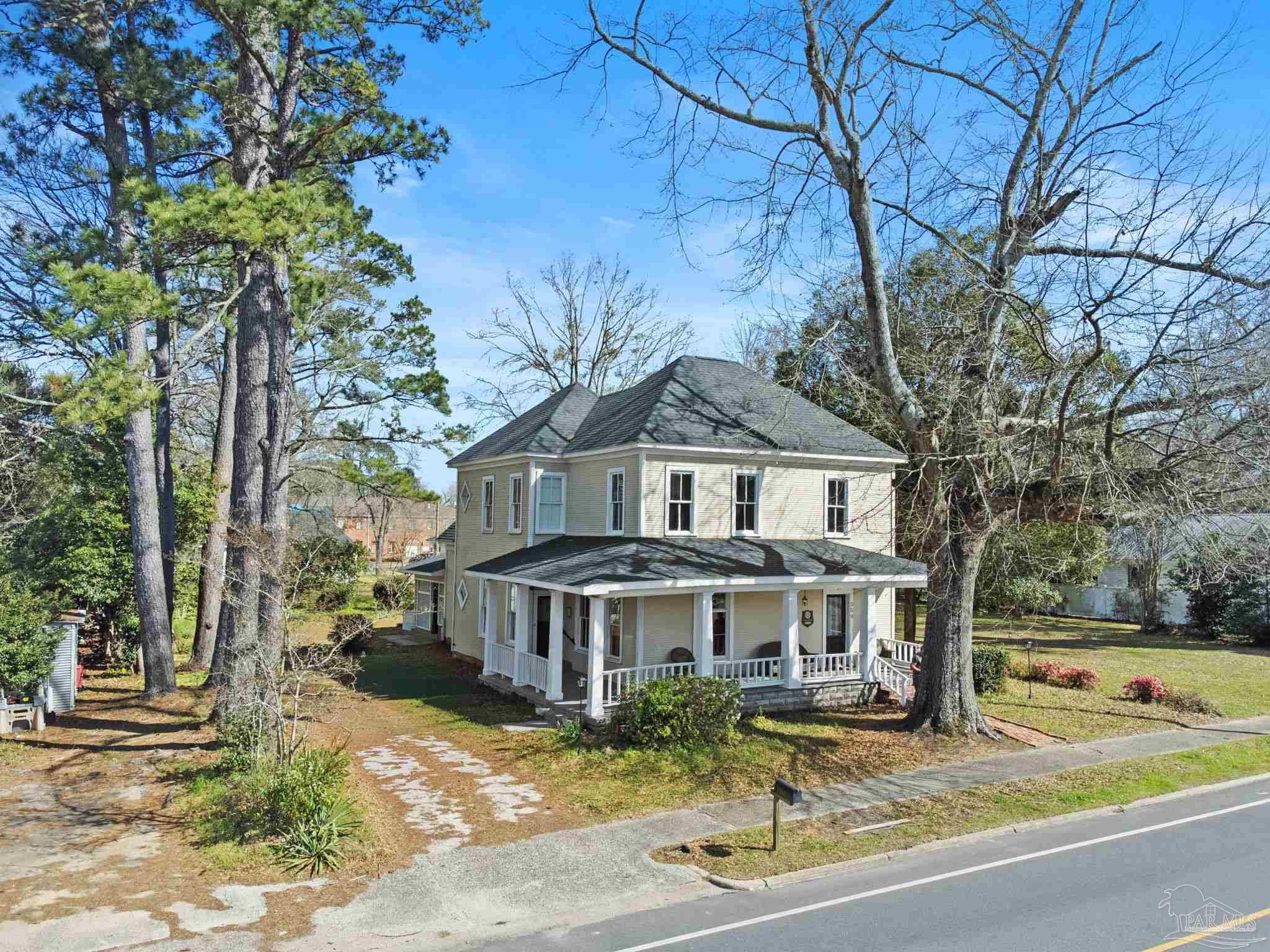 a view of a white house with a large tree and yard