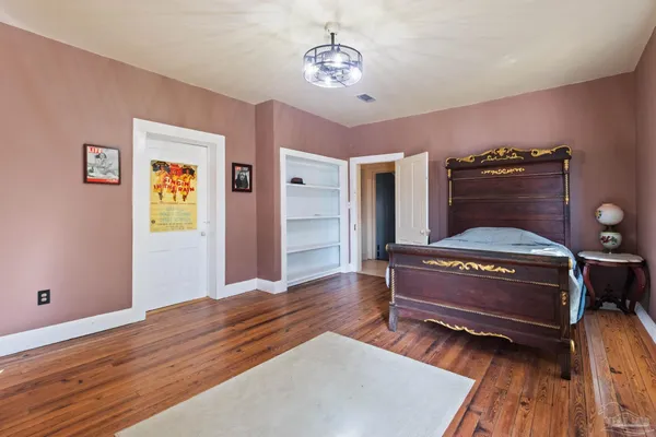 a bedroom with a bed piano and wooden floor