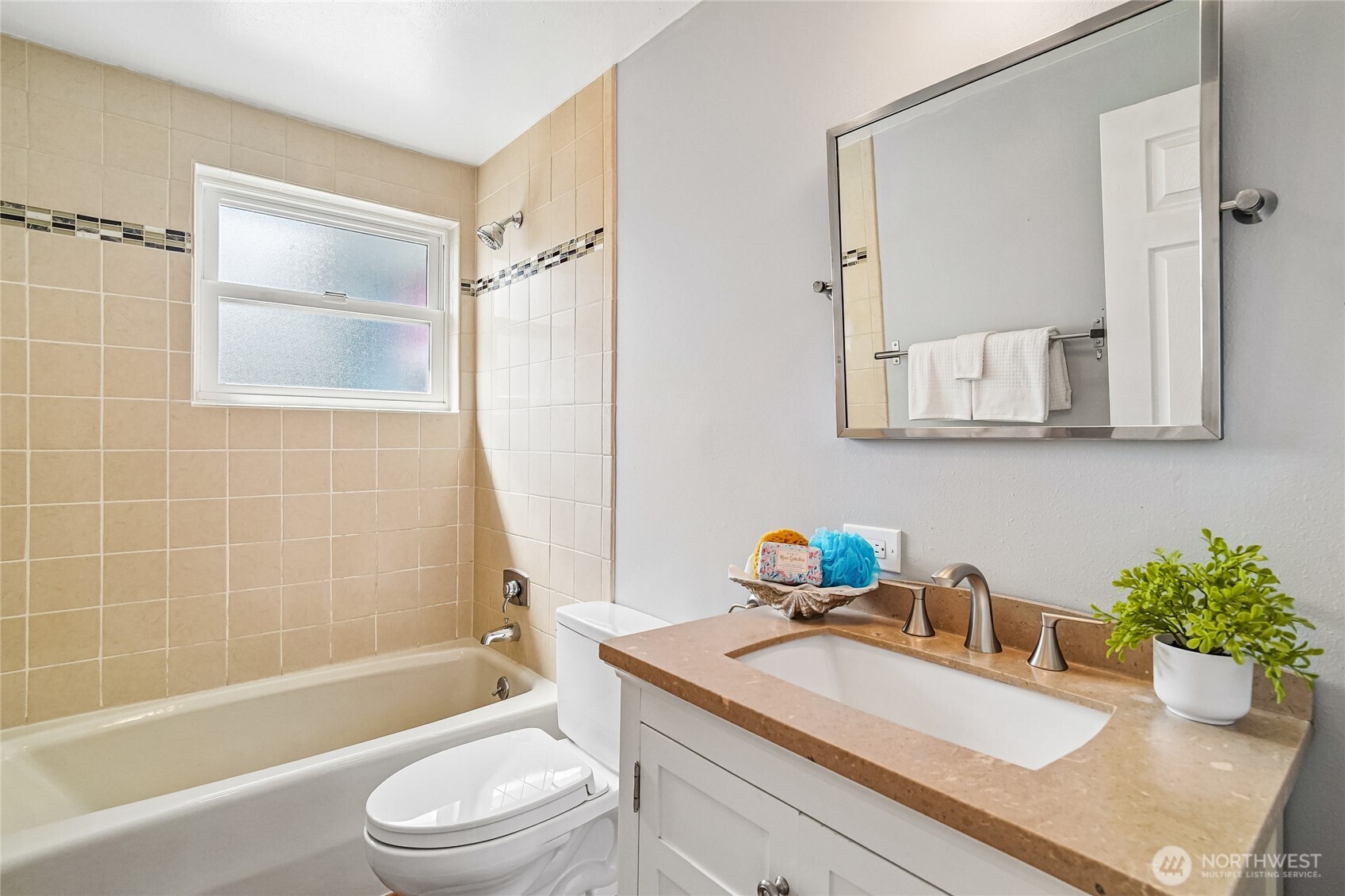 7313 25th Avenue Northwest Seattle, WA 98117 - Photo 13 of 40 a bathroom with a granite countertop sink a toilet a mirror a vanity a bathtub and shower
