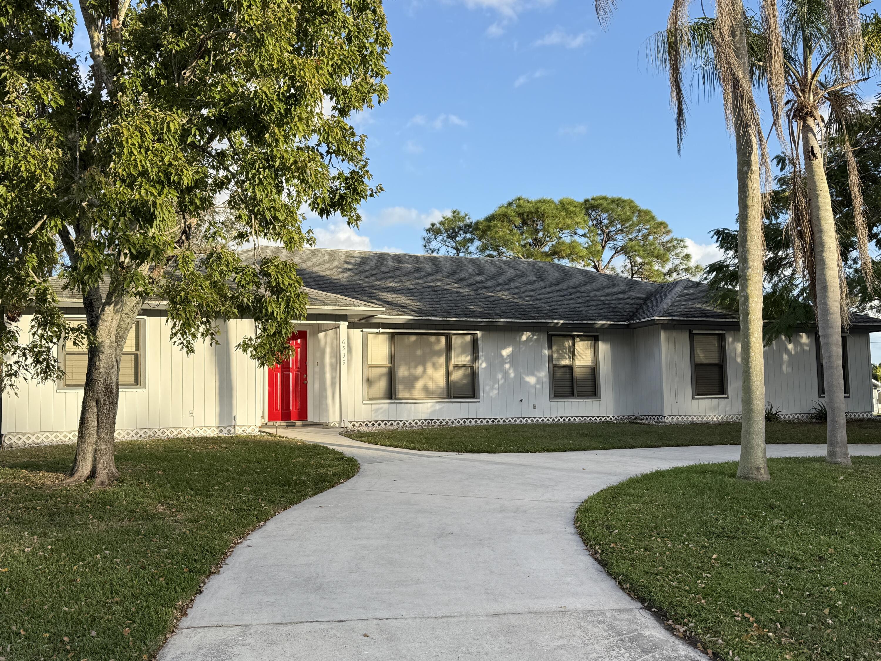 6539 Southeast Held Court Stuart, FL 34997 - Photo 1 of 34 a front view of a house with a yard and garage