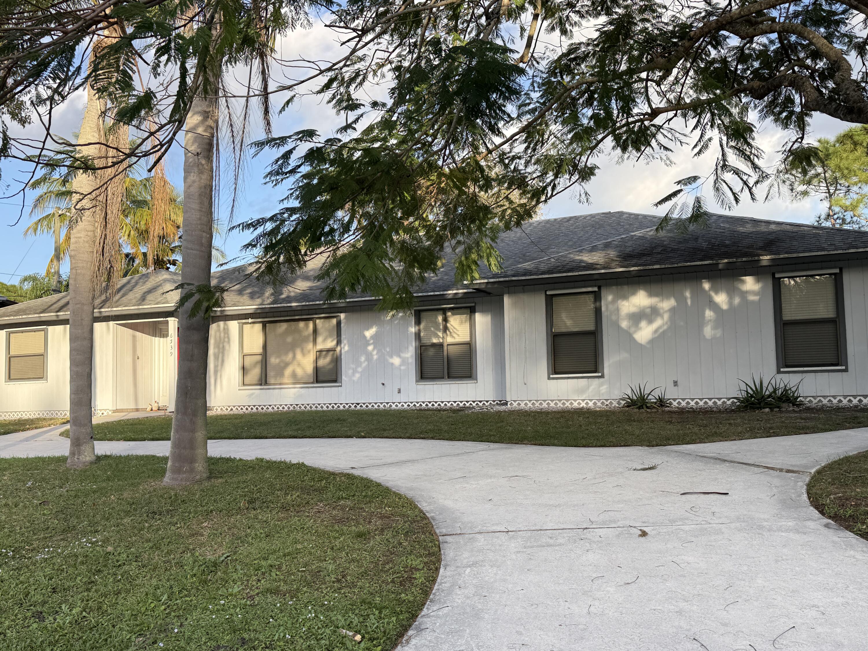 6539 Southeast Held Court Stuart, FL 34997 - Photo 2 of 34 a front view of a house with garden