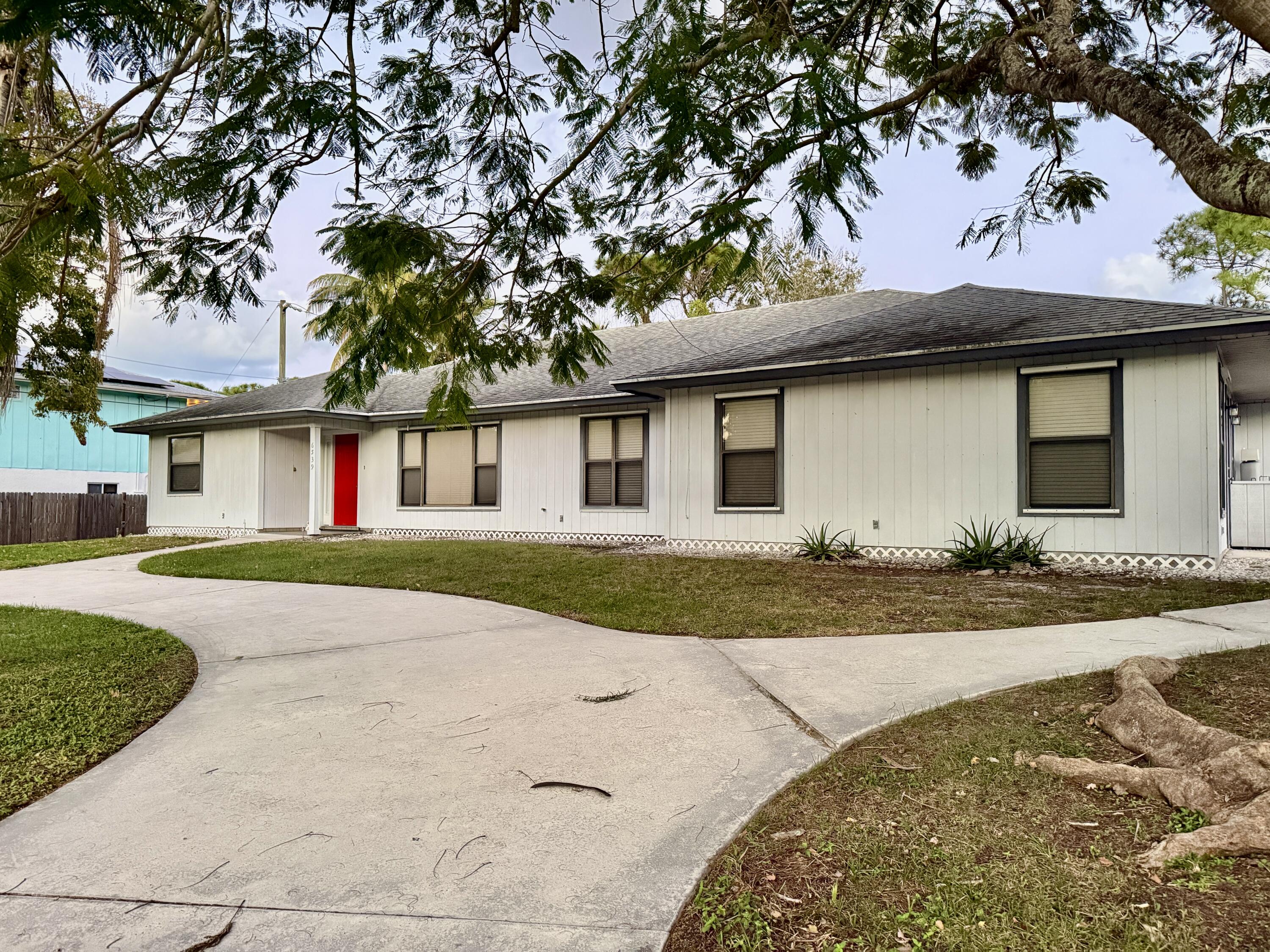6539 Southeast Held Court Stuart, FL 34997 - Photo 31 of 34 a front view of a house with a yard and garage