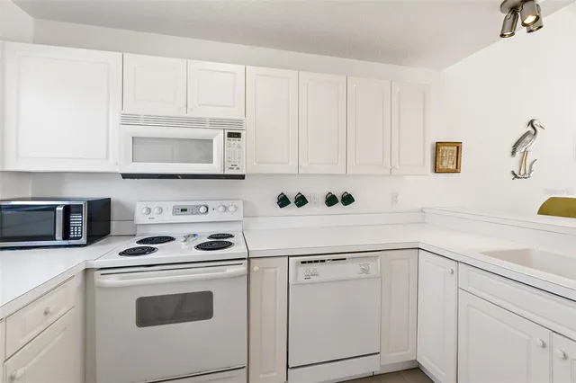 a kitchen with white cabinets and white appliances