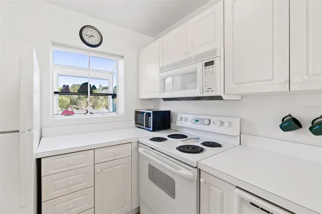 a kitchen with white cabinets and white appliances