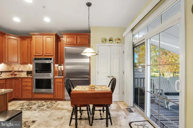a kitchen with stainless steel appliances granite countertop a stove a refrigerator a kitchen island a table and chairs