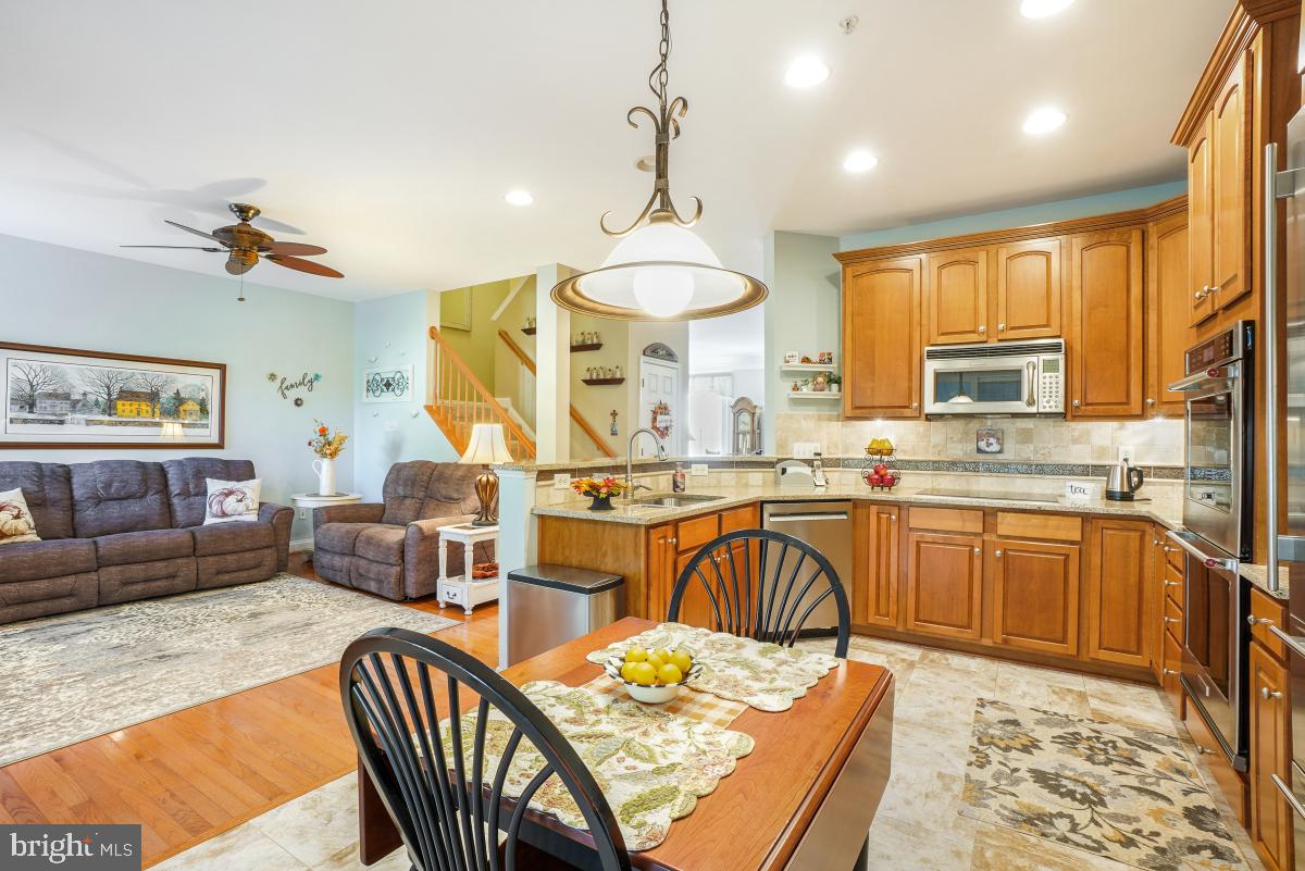7606 Vulpe Court Odenton, MD 21113 - Photo 16 of 45 a large kitchen with stainless steel appliances granite countertop a stove a sink dishwasher a dining table and chairs with wooden floor