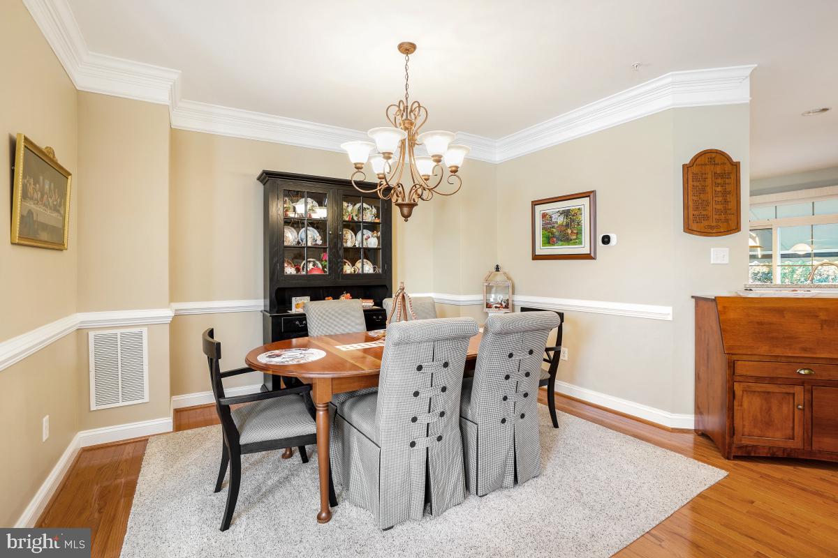 7606 Vulpe Court Odenton, MD 21113 - Photo 8 of 45 a dining room with wooden floor a chandelier a wooden table and chairs