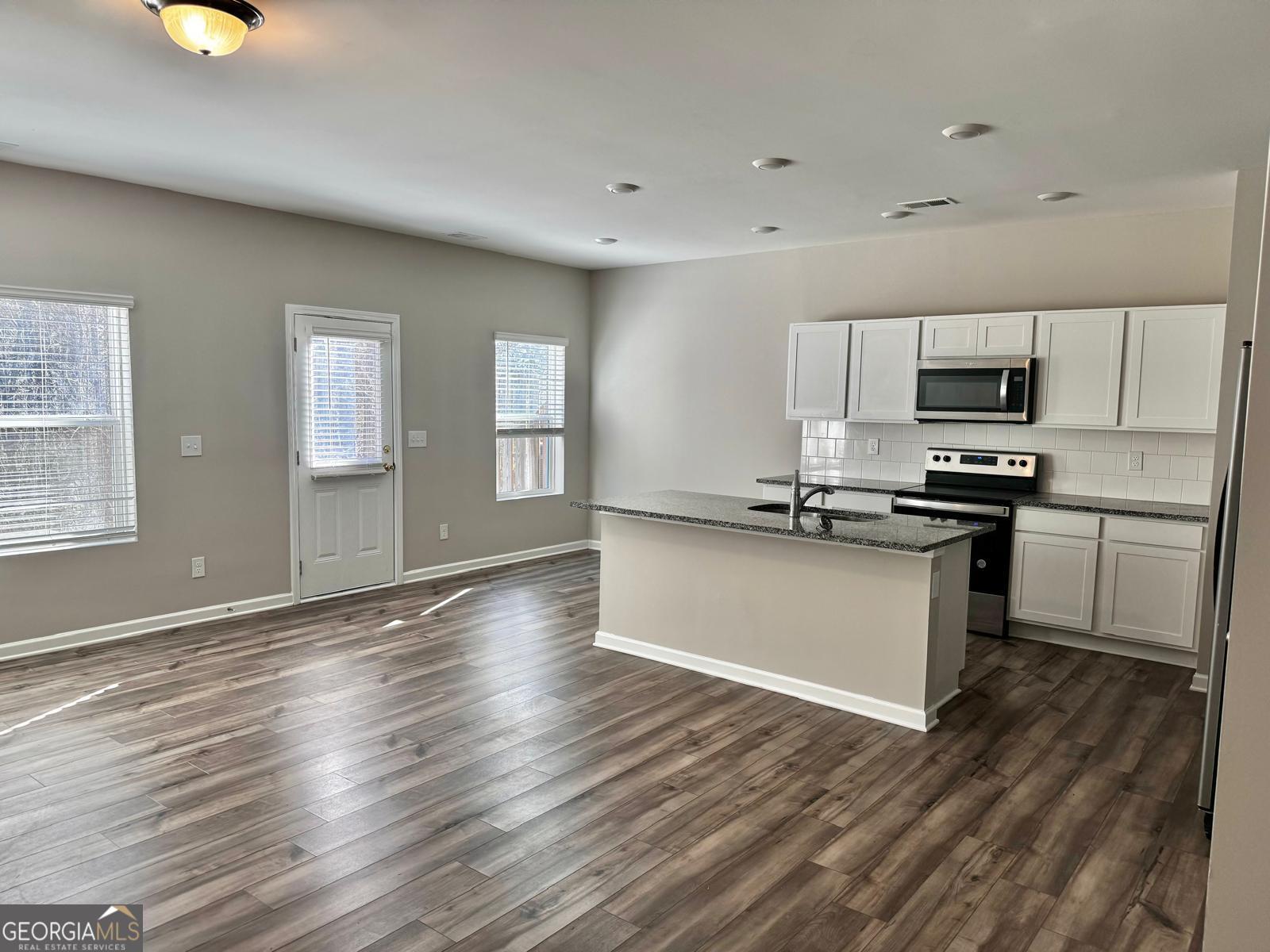 1397 Ben Park Way Grayson, GA 30017 - Photo 3 of 17 a kitchen with granite countertop a refrigerator and a stove top oven