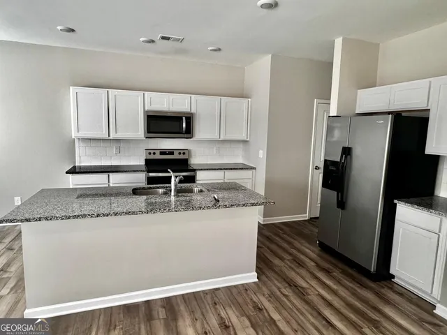 a kitchen with stainless steel appliances granite countertop a refrigerator a stove and a sink