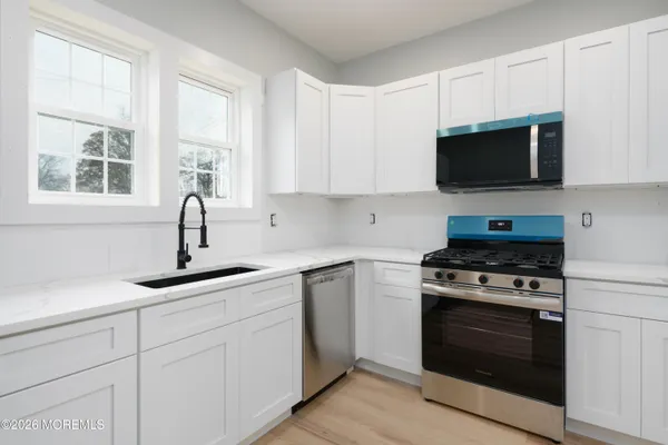 a kitchen with white cabinets and appliances