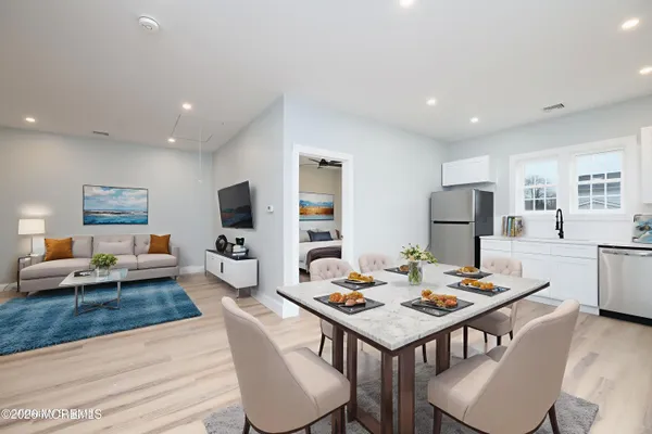 a living room with stainless steel appliances furniture a rug and a kitchen view
