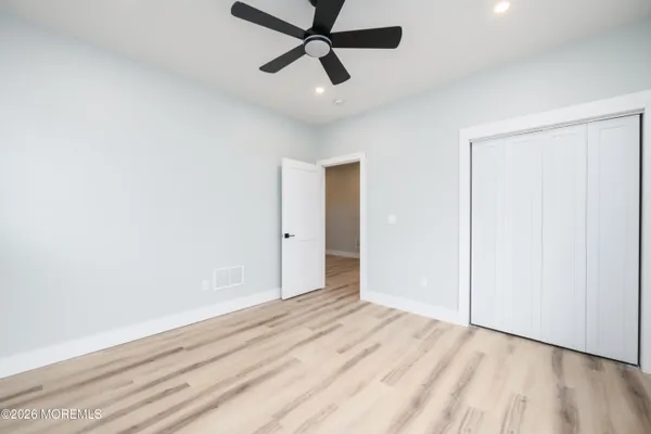 a view of empty room with wooden floor and ceiling fan