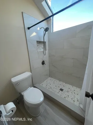 a white toilet sitting next to a bath tub and a shower