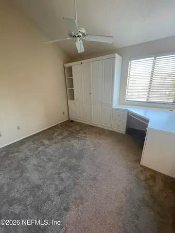 an empty room with windows and fan