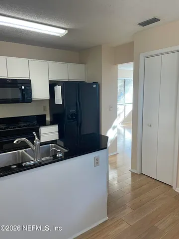 a kitchen with stainless steel appliances a sink and wooden floor