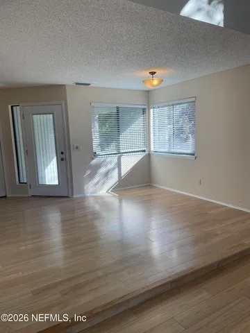 an empty room with wooden floor and windows