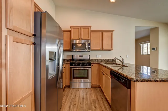 a kitchen with granite countertop a sink cabinets stainless steel appliances and a counter top space