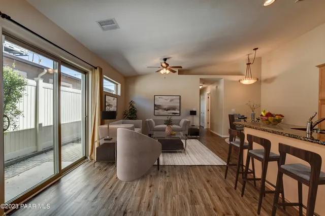 a living room with furniture a large window and wooden floor