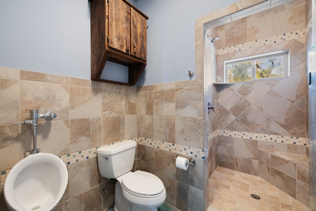 1292 Upper Turtle Creek Road Kerrville, TX 78028 - Photo 20 of 40 Full bath with a stall shower, tile walls, and wainscoting