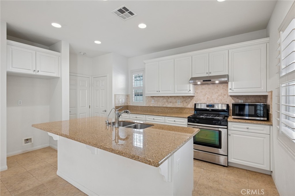 93 Keepsake Irvine, CA 92618 - Photo 13 of 25 a kitchen with stainless steel appliances granite countertop a sink a stove and a refrigerator