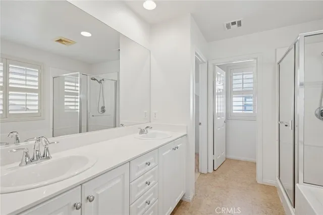 a spacious bathroom with double sink a mirror and a shower