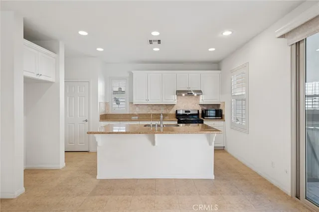 a large kitchen with stainless steel appliances granite countertop a stove a refrigerator a sink and a microwave