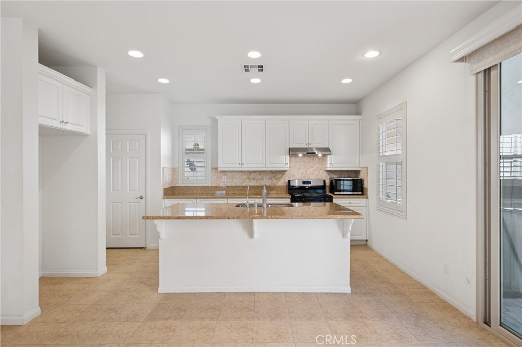 93 Keepsake Irvine, CA 92618 - Photo 9 of 25 a large kitchen with stainless steel appliances granite countertop a stove a refrigerator a sink and a microwave