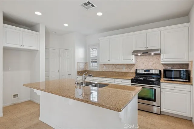 a kitchen with granite countertop a sink and white cabinets