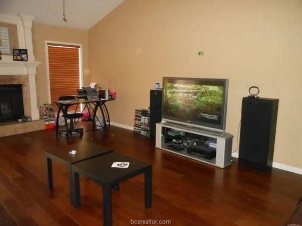 a living room with furniture a flat screen tv and wooden floor