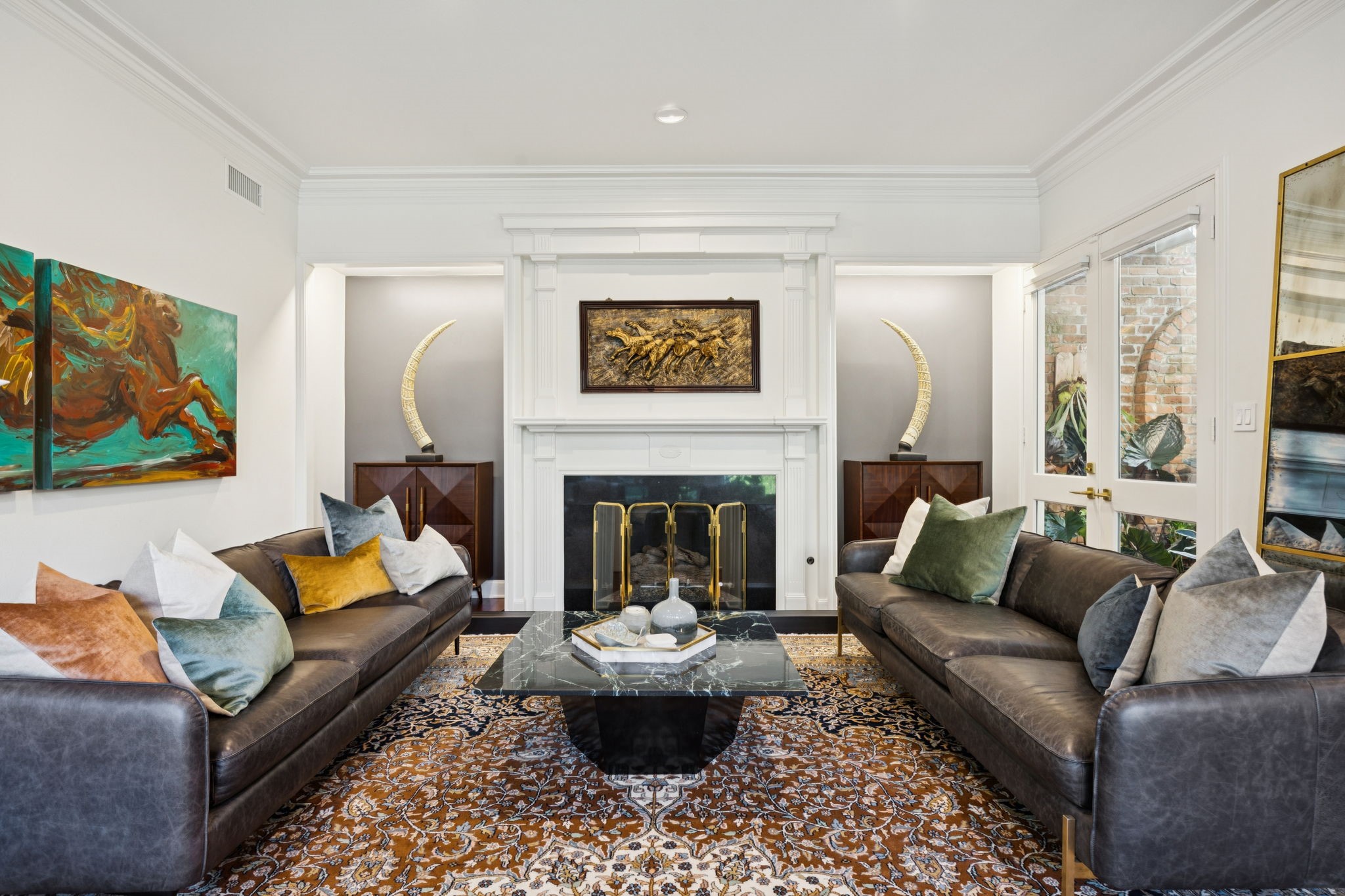 4964 Post Oak Timber Drive Houston, TX 77056 - Photo 12 of 48 This sophisticated living room blends classic architecture with modern style, featuring a grand white fireplace framed by elegant accent walls. Natural light filters through French doors, enhancing the room’s warm sunlit glow.