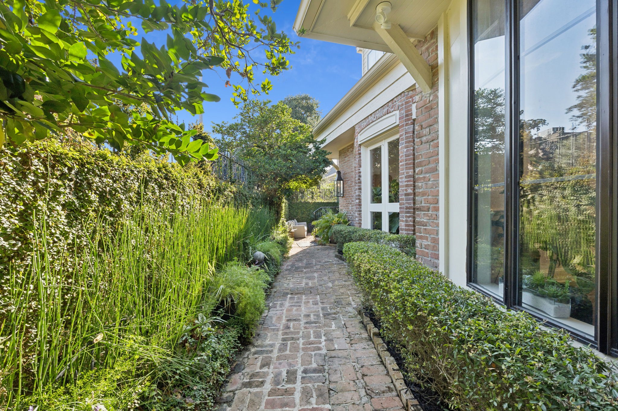 4964 Post Oak Timber Drive Houston, TX 77056 - Photo 7 of 48 A brick pathway leads to a cozy seating area tucked amid greenery, where the sound of rustling leaves and birds replaces city noise.