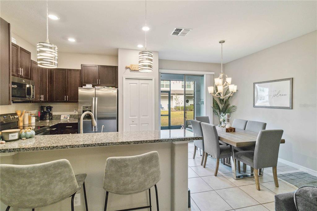 14339 Easy Goer Street Ruskin, FL 33573 - Photo 11 of 49 a dining room with stainless steel appliances kitchen island granite countertop a table chairs and a refrigerator
