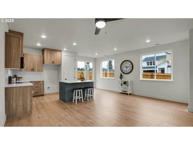 a living room with stainless steel appliances kitchen island granite countertop a dining table chairs and a refrigerator