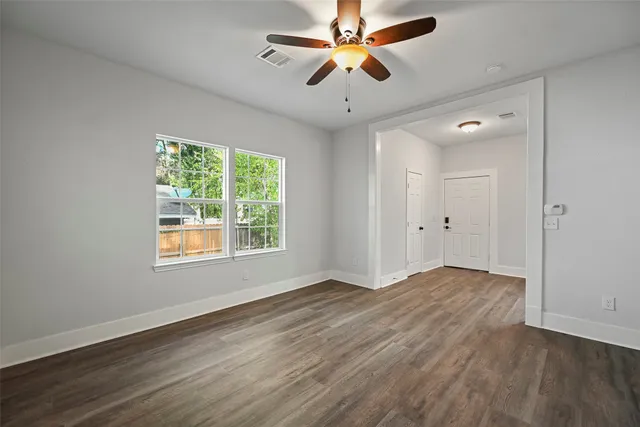 a view of an empty room with window and wooden floor