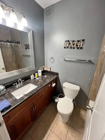 a bathroom with a granite countertop toilet sink and mirror