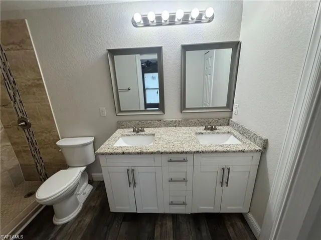a bathroom with a granite countertop sink a toilet and a mirror