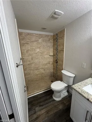 a bathroom with a granite countertop toilet a sink and a shower