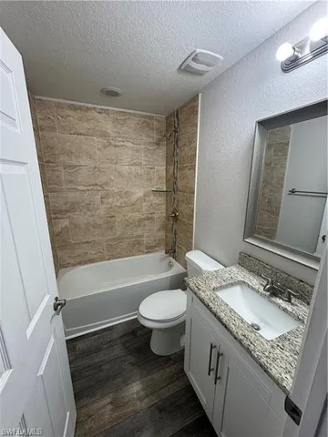 a bathroom with a granite countertop sink a toilet a mirror a bathtub and shower
