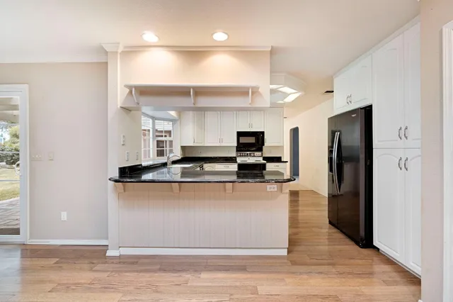 a kitchen with stainless steel appliances granite countertop a refrigerator a sink a stove and oven