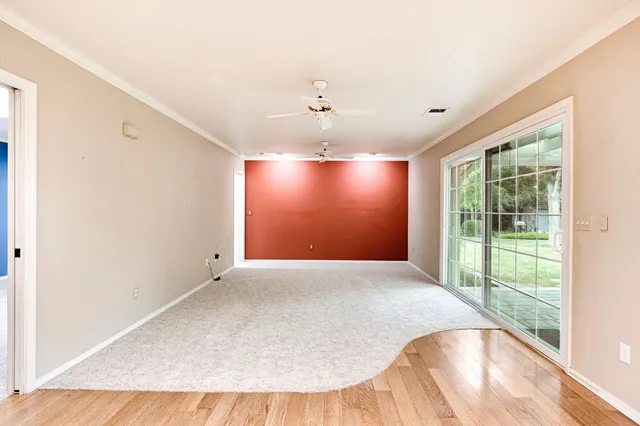 an empty room with windows and ceiling fan