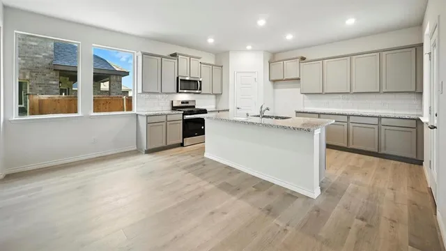 a large kitchen with stainless steel appliances granite countertop a stove top oven a sink dishwasher and a microwave oven on granite countertops