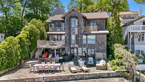 a view of a brick house with large windows and a table and chairs
