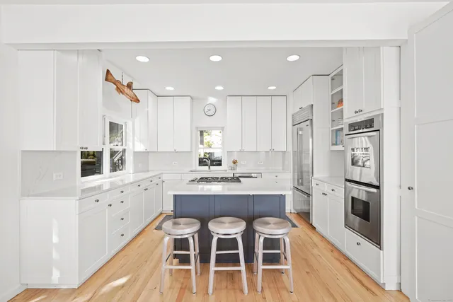 a kitchen with white cabinets and wooden floor