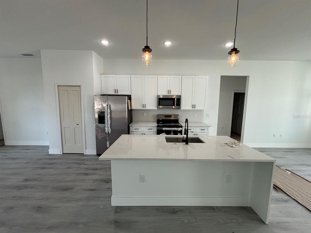 7518 Southwest 128th Street Ocala, FL 34473 - Photo 4 of 5 a large kitchen with stainless steel appliances kitchen island a large counter top and wooden floors